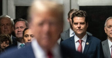 Matt Gaetz behind Donald Trump, both wearing suits