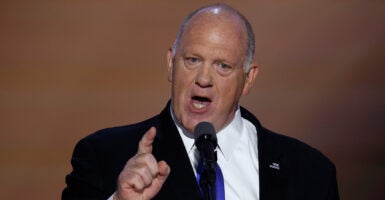 Thomas Homan in a dark suit and tie speaks on stage, gesturing by pointing his finger