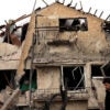 a man in a black shirt walks by a house destroyed by a missile attack in Israel