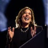 Kamala Harris in a black outfit and pearls laughs and claps her hands