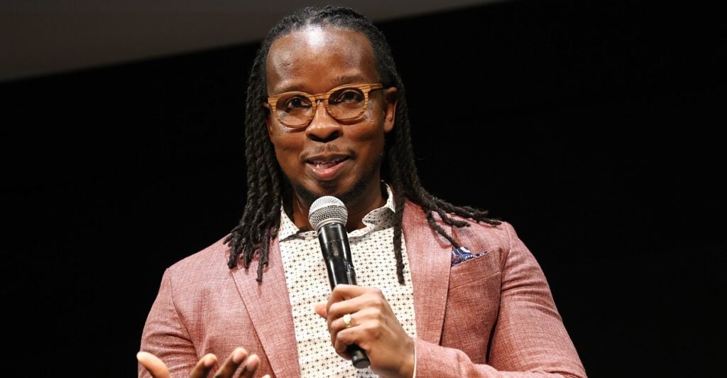 Ibram X. Kendi speaks onstage holding a microphone at the premiere of a Netflix movie.