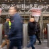 In front of The New York Times building, protestors hold signs.