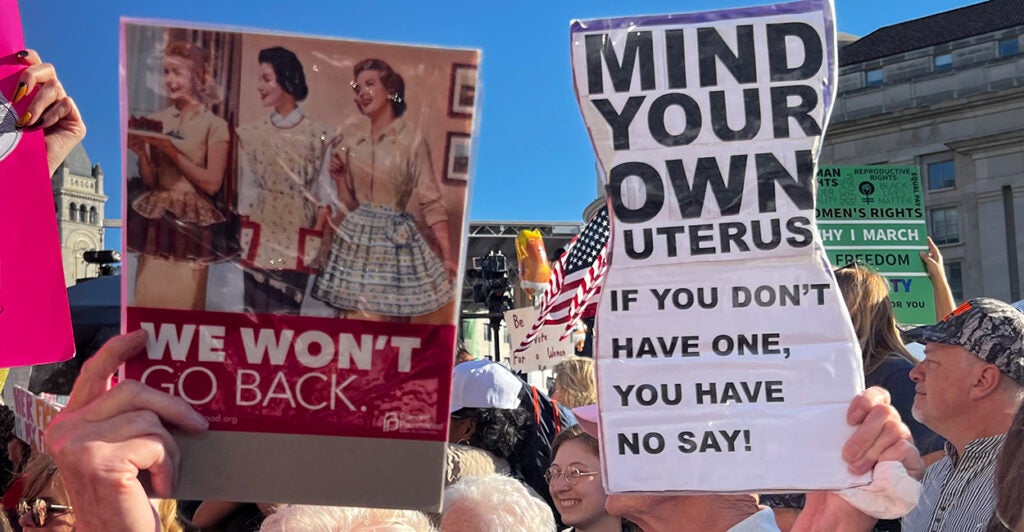 Signs read, "We Won't Go Back" and "Mind your own uterus."