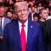 President Donald Trump in a blue suit and red tie surrounded by supporters