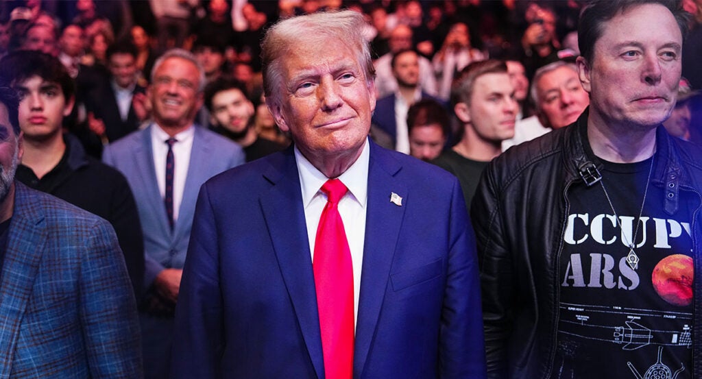 President Donald Trump in a blue suit and red tie surrounded by supporters