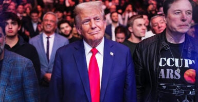 President Donald Trump in a blue suit and red tie surrounded by supporters