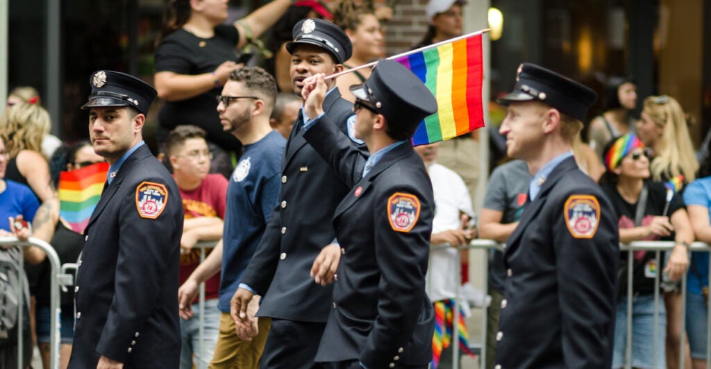 New York City firefighters in uniform March in the annual Gay Pride Parade And wave a Small pride flag