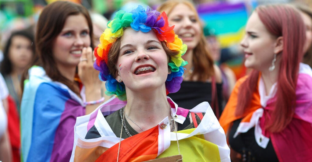 Several gay and transgender teen girls dressed in colorful flags at a parade