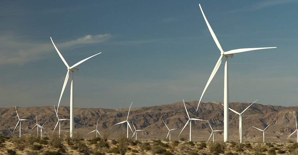 A field of large white windmills in the desert of Southern California against dark blue sky.