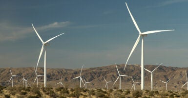 A field of large white windmills in the desert of Southern California against dark blue sky.