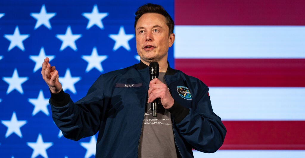 Elon Musk speaks at an event in Lancaster, Penn., with a U.S. flag as a backdrop.