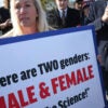 Rep. Marjorie Taylor Greene, R-Ga., holds a sign reading, "There are two genders: Male and female. Trust the science."