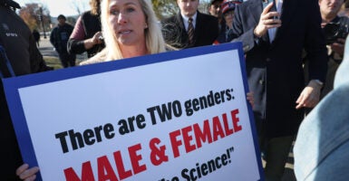 Rep. Marjorie Taylor Greene, R-Ga., holds a sign reading, "There are two genders: Male and female. Trust the science."