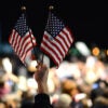 Two small hand-held U.S. flags emerge from a crowd.