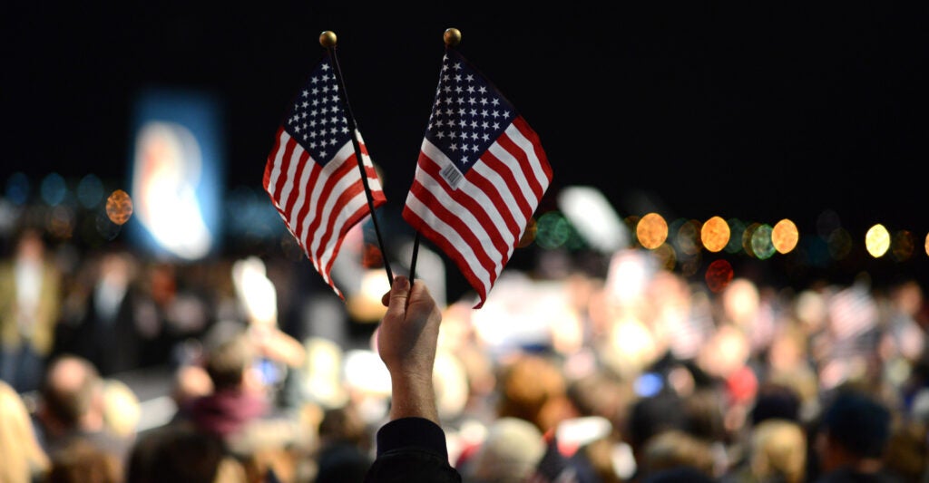 Two small hand-held U.S. flags emerge from a crowd.