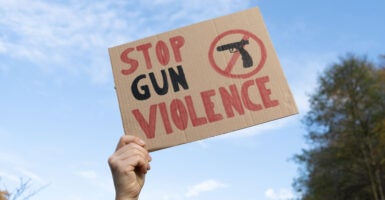 A hand holds aloft a homemade "stop gun violence" sign.