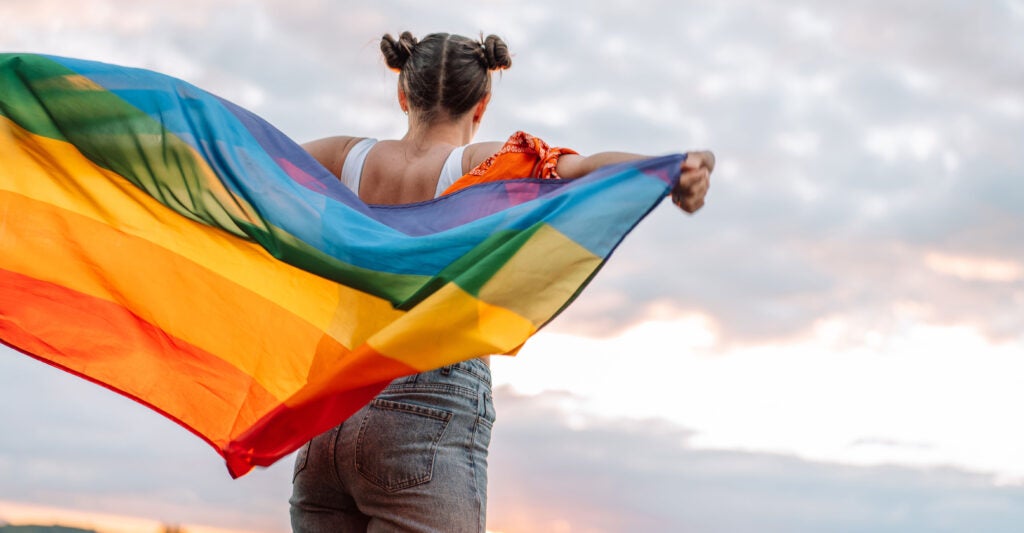 What appears from behind to be a young girl waving an LGBT flag in a secluded rural area