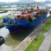 A cargo ship and tugboat sail through the Cocoli Locks of the Panama Canal