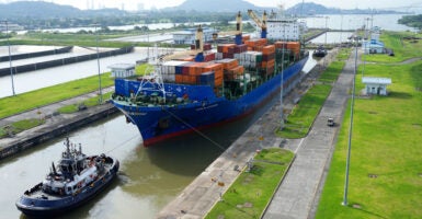 A cargo ship and tugboat sail through the Cocoli Locks of the Panama Canal