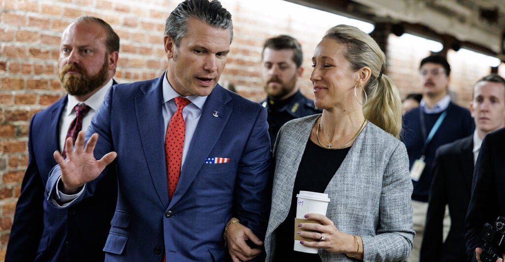 Pete Hegseth, in a blue suit and red tie, walks arm in arm with wife Jennifer Rauchet after visiting Sen. Tom Cotton on Thursday on Capitol Hill.