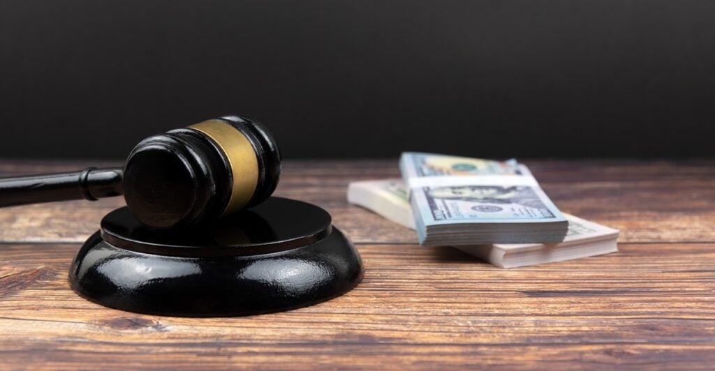 A judge's gavel lays on a desk next to a pile of money.