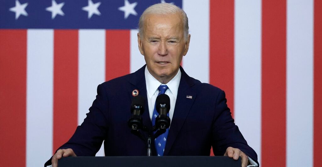 President Joe Biden stands at a podium with an American flag behind him.