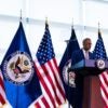 Richard Verma, deputy secretary of State for Management and Resources, stands at a podium with several flags behind him.