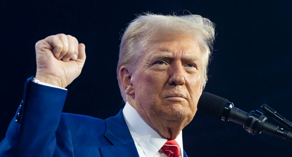 Donald Trump raises his fist in a blue suit