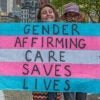 An activist holds a sign reading, "Gender-affirming care saves lives."