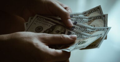 A person's hands holding $100 bills.