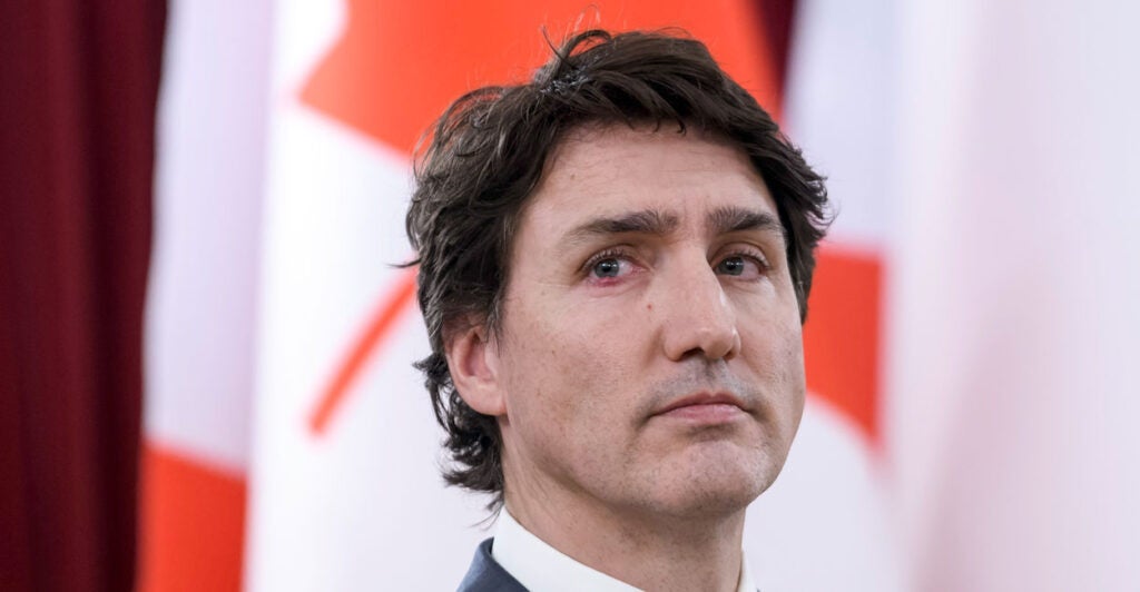 Close-up of Canadian Prime Minister Justin Trudeau with the Canadian flag in the background.