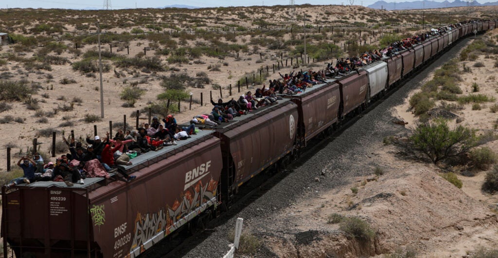 Migrants ride on top of freight cars.