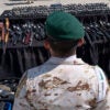 A Mexican soldier stands in front of guns.