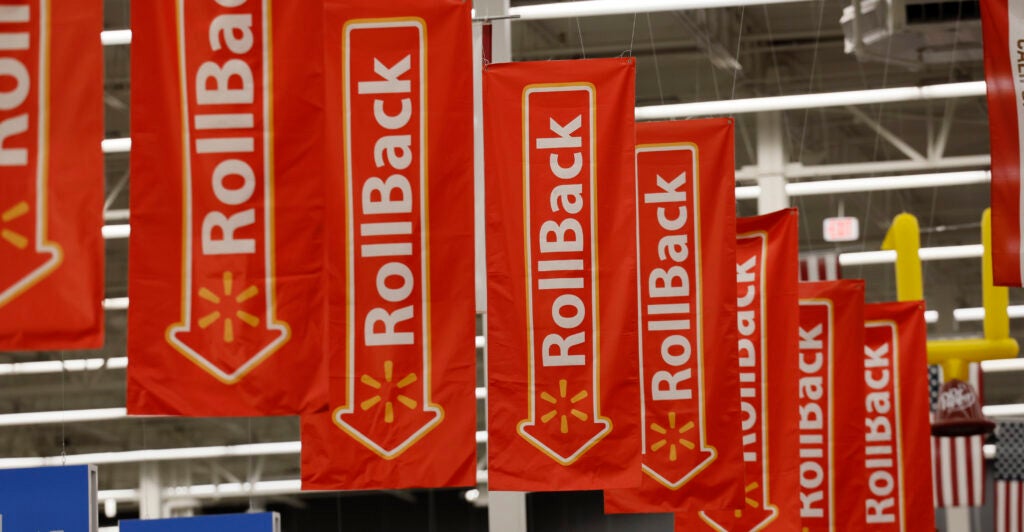 Multiple red "Rollback" banners with white lettering hang in a Walmart Supercenter.