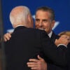 Hunter Biden in a black suit hugs his father, Joe Biden, also in a black suit.