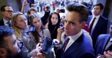 Sen. Josh Hawley stands outside surrounded by a flock of reporters.