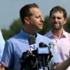 U.S. Representative Jared Moskowitz stands at a podium with microphones and talks to reporters.