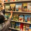 Children reach for the Tintin books on a shelf.