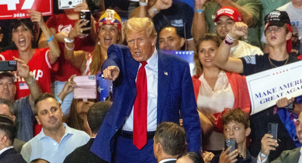 Donald Trump points in a blue suit at a rally