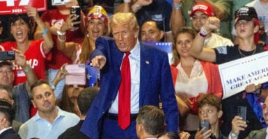 Donald Trump points in a blue suit at a rally