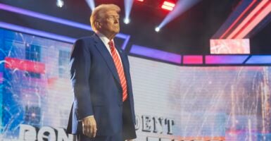 President-elect Donal Trump stands on a stage with his arms by his side looking forward.