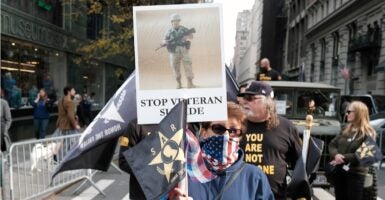 A woman holds up a sign at a rally that says, "Stop Veteran Suicide."