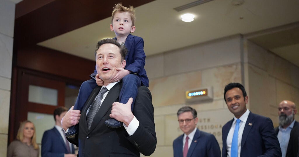 Elon Musk at the Capitol with a young son riding piggyback