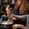 Mother and young daughter cook side-by-side at a gas stove