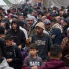 a large, packed crowd of Palestinians, mostly men, at a United Nations school in Gaza waiting to receive aid