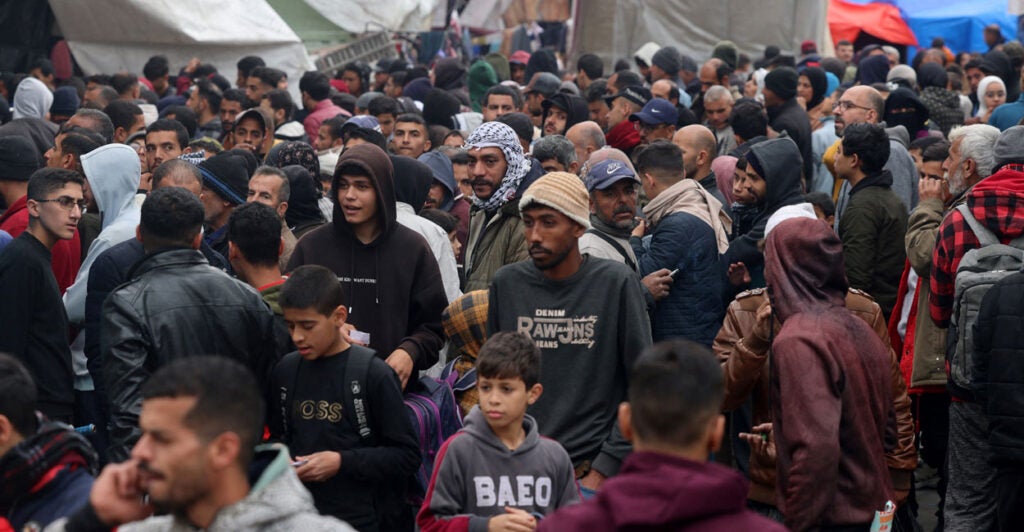 a large, packed crowd of Palestinians, mostly men, at a United Nations school in Gaza waiting to receive aid