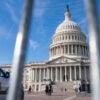 The U.S. Capitol building as seen through the vertical bars of a bike rack