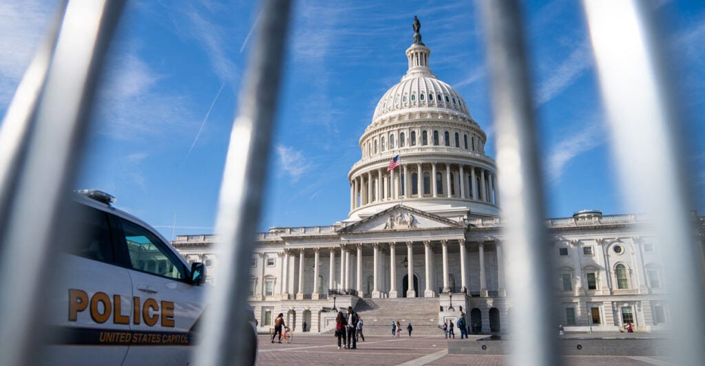 The U.S. Capitol building as seen through the vertical bars of a bike rack