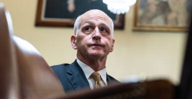 Democratic Rep. Adam Smith in a blue suit and gold tie sitting in a House meeting room