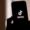 A silhouetted cellphone displays the social media app TikTok